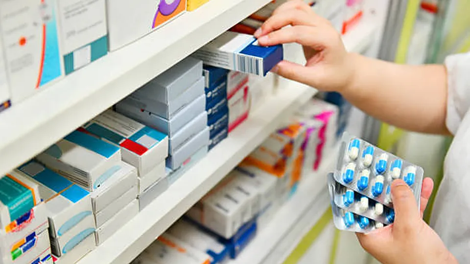 Hand taking a medicine box from a pharmacy shelf, with blister packs